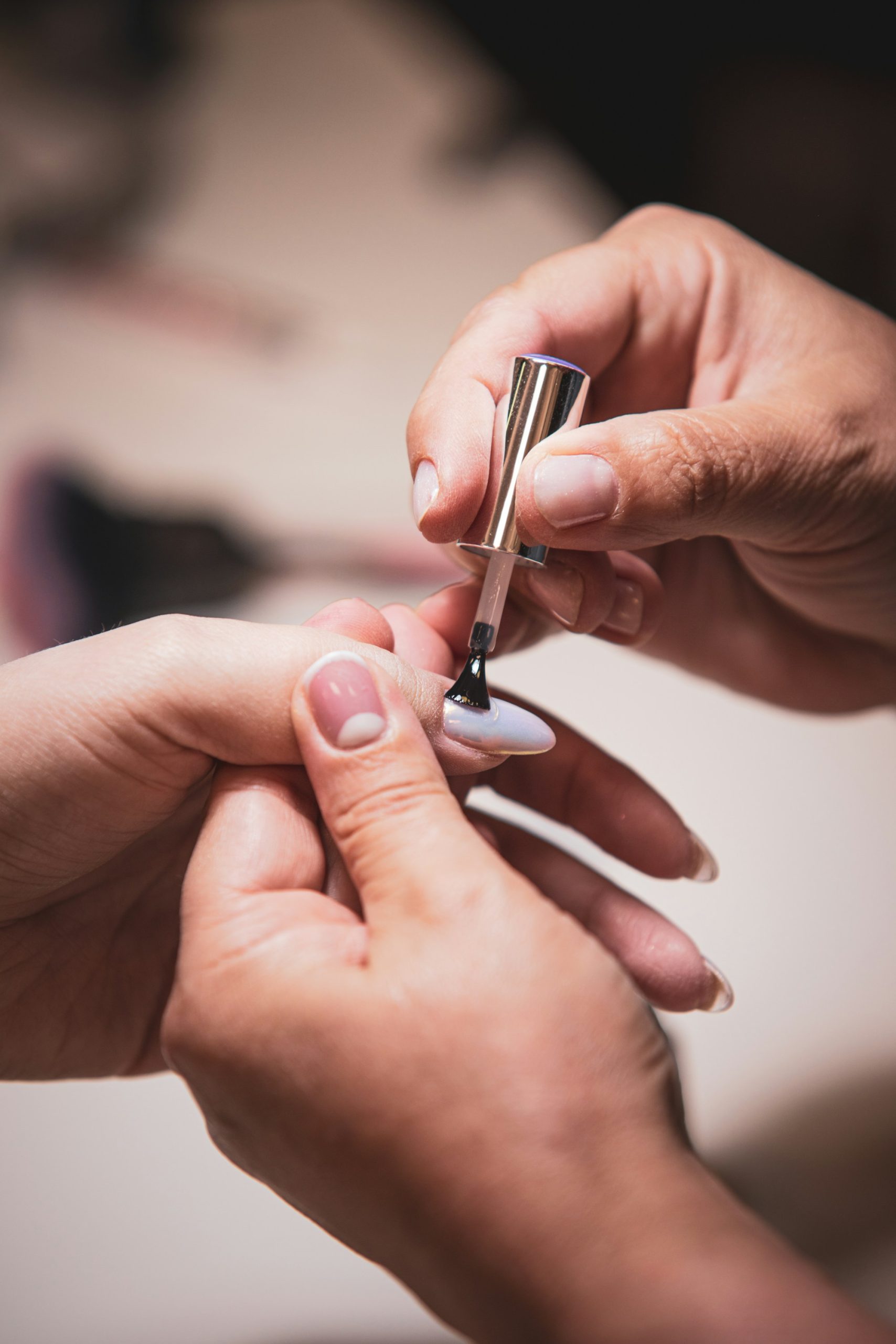 A nail technician applying polish with a fine brush