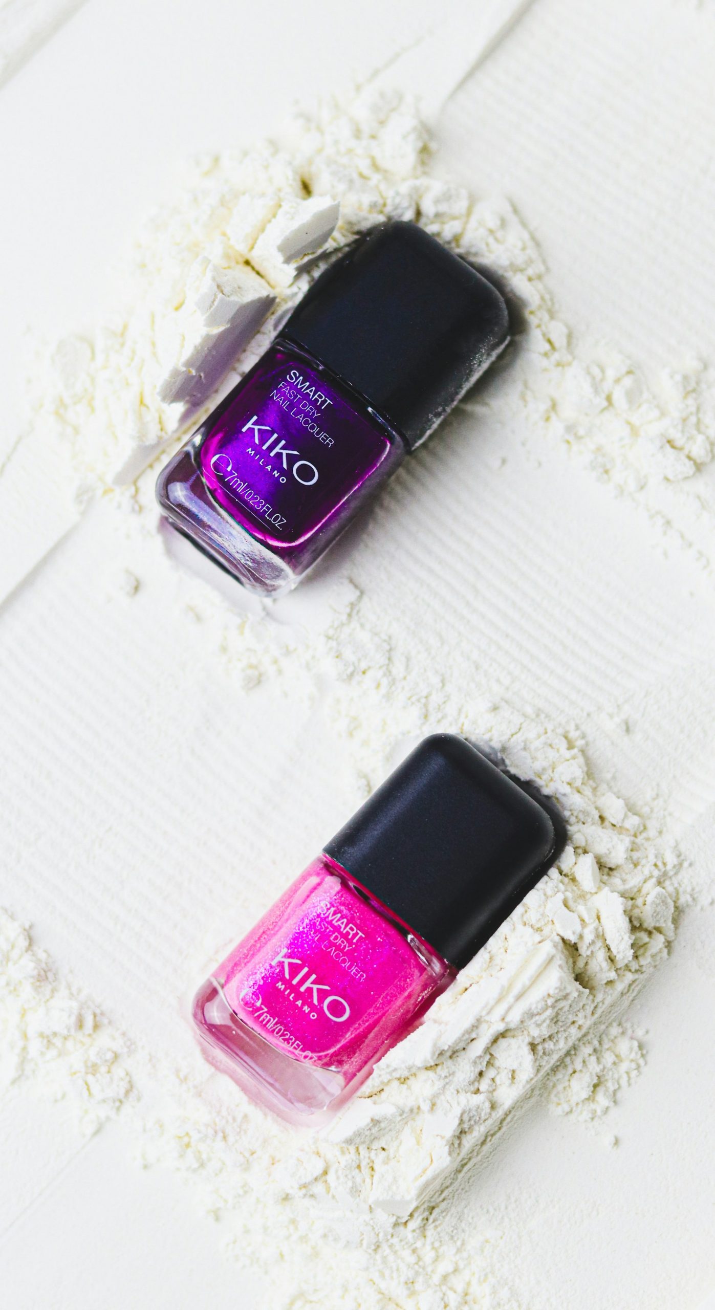 Two bottles of nail polish in purple and pink