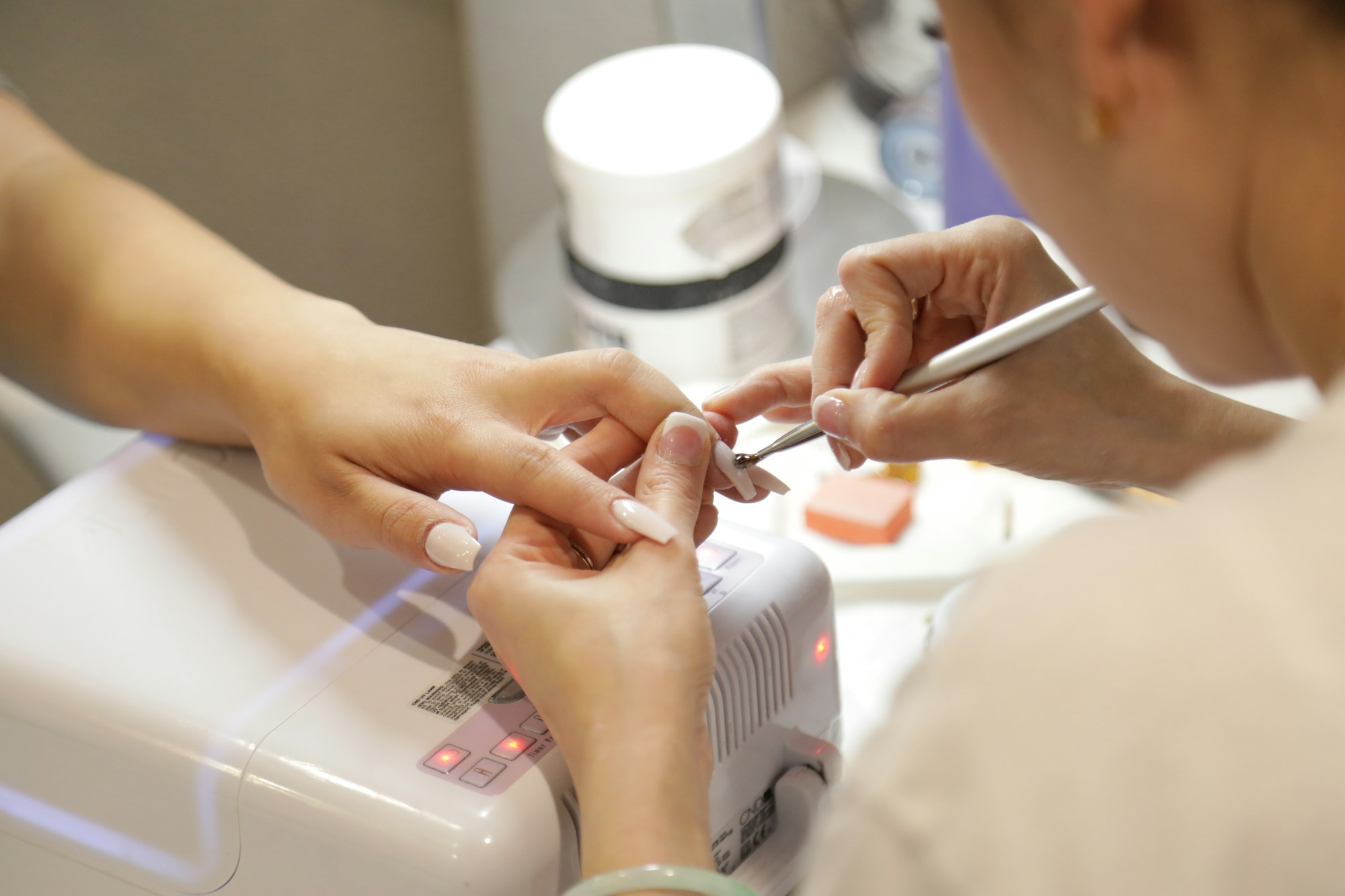A nail technician perfecting a client’s manicure at a bright studio desk