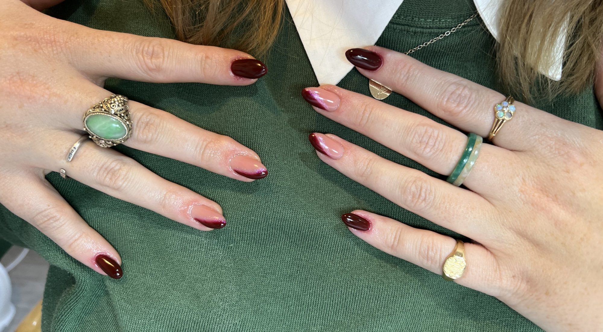 Almond nails in deep burgundy and burgundy French tips, worn with gold rings