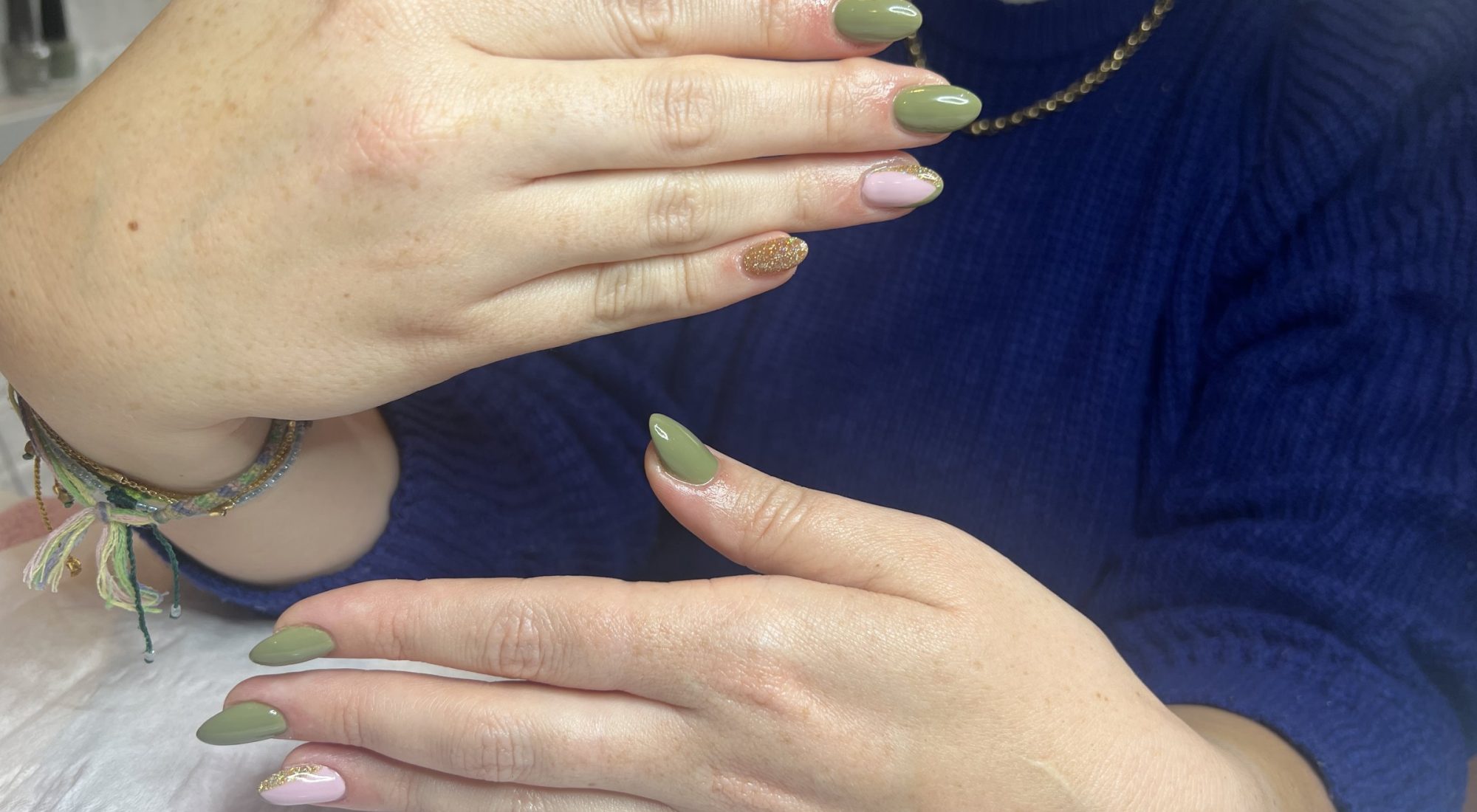 Sage green almond nails with a gold-flecked accent nail
